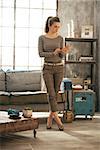 Full length portrait of young woman standing in loft apartment