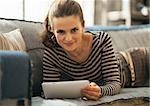 Young woman laying on couch and using tablet pc in loft apartment