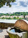 Image of a small well, river Inn and riverside with pilgrimage Maria Hilf in Passau, Germany