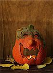 Halloween still life - pumpkin with  yellow leaves on the wooden background