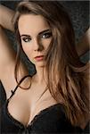 Short portrait of beautiful, young, sensual woman with long, straight, brown hair, dark make up, wearing sexy, balck lingerie, lookong at the camera.