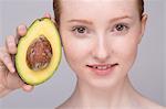 Portrait of young woman, holding avocado