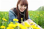 Portrait of young woman in earphones in dandelion field