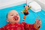 Contented 7 month old baby girl playing with dangling teddybear