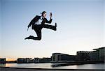 Mid adult businessman jumping mid air, Copenhagen harbor, Denmark