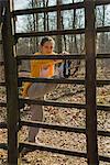 Young woman touching toes on forest assault course