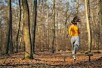 Young woman jumping fence on assault course in forest