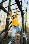 Young woman on climbing frame on assault course in forest