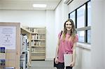 Young woman holding laptop in library