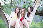 Three female friends sitting in a hammock, Piemonte, Italy