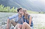 Young man kissing girlfriend on Toce riverbank, Piemonte, Italy