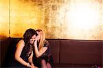 Two female friends whispering in nightclub
