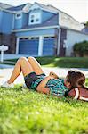 Girl laying on football in grass outside house