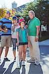 Portrait of happy multi-generation family playing baseball in street