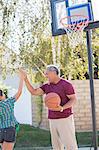 Grandfather and granddaughter high fiving at basketball hoop