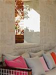 Stone wall  behind patio bench with cushions