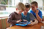 Three boys playing with digital tablet