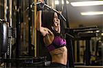 Mid adult woman in gym doing pectoral exercise