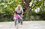 Grandfather playing hopscotch with toddler granddaughter