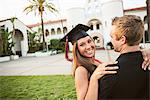 Female graduate hugging man