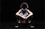 Basketball player sitting on basketball