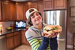 Teenage boy in kitchen holding sandwich