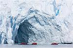 Lindblad Expeditions guests in a Zodiac near an arch in a glacier face in Paradise Bay, Antarctica, Polar Regions