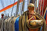 Rows of ropes hanging on large wooden and metal pegs on ancient sailing vessel board. Shallow depth of focus.