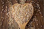 Loose grains of farro in and around a wooden spoon.