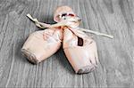 Old used  ballet pointe shoes on vintage wooden background