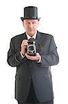 Middle aged  photographer in a retro business suit with retro camera isolated on white.