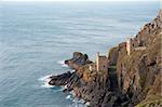 View of the two ruined engine houses of the Crown Mines , Botallack, Cornwall perched on a cliff overlooking the undersea shaft extending under the ocean floor in search of tin, now a heritage site