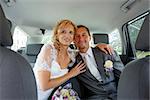 beautiful young wedding couple, blonde bride with flower and her groom in car, wide shoot