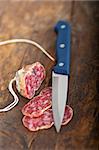 slicing italian salame pressato pressed over old wood table