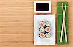 Sushi set, chopsticks and soy sauce over bamboo table with copy space