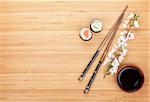 Maki sushi, chopsticks and soy sauce on bamboo wooden table background with copy space