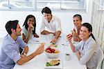 Workers laugh while eating sandwiches for lunch in the office