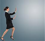 Businesswoman in suit standing and pushing on grey background