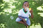 Little boy blowing bubbles in the park on a sunny day