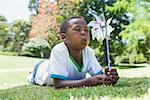 Little boy blowing pinwheel in the park on a sunny day