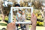 Hand holding tablet pc showing elderly couple with their bikes