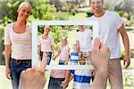 Hand holding tablet pc showing adorable family in the park