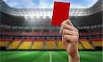 Hand holding up red card against stadium full of germany football fans