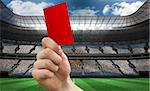 Hand holding up red card against stadium full of argentina football fans