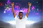 Excited handsome football fan cheering against fireworks exploding over football stadium