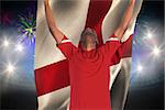 Excited handsome football fan cheering against fireworks exploding over football stadium and england flag