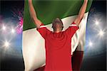 Excited handsome football fan cheering against fireworks exploding over football stadium and italy flag