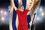 Excited football player cheering against fireworks exploding over football stadium and uruguay flag