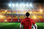 Spain football player holding ball against stadium full of spain football fans