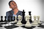 Composite image of young businessman thinking with chessboard
